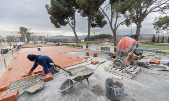 Dos obrers treballant en la taulada de l'edifici de vestuaris de la zona esportiva de La Bòbila